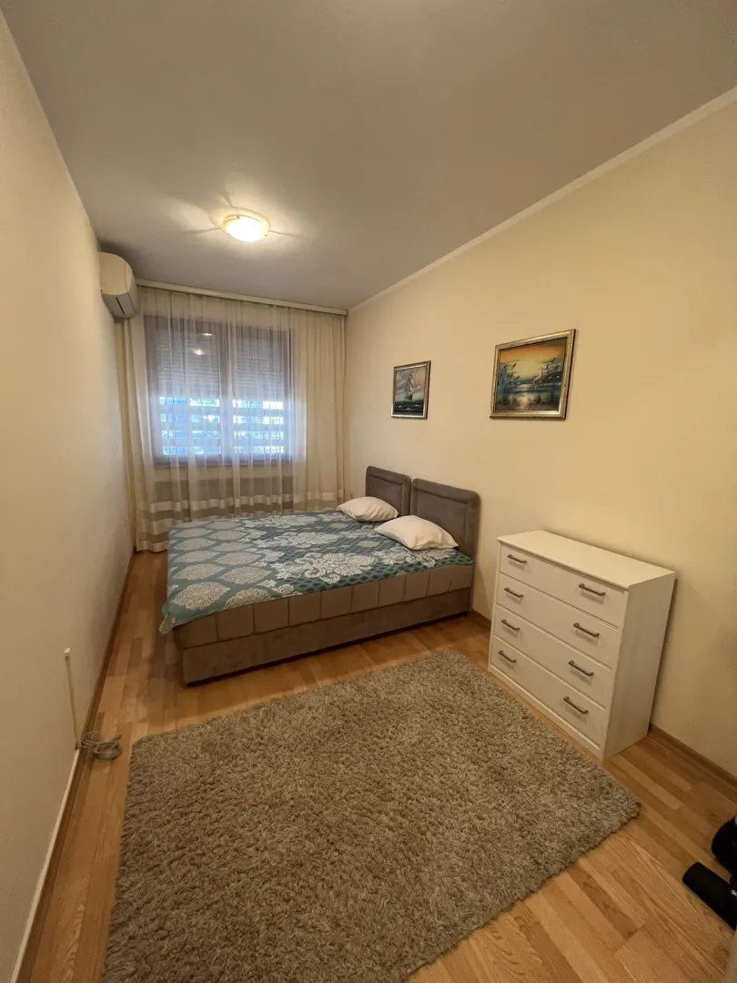 A simply furnished bedroom with a double bed and a chest of drawers.