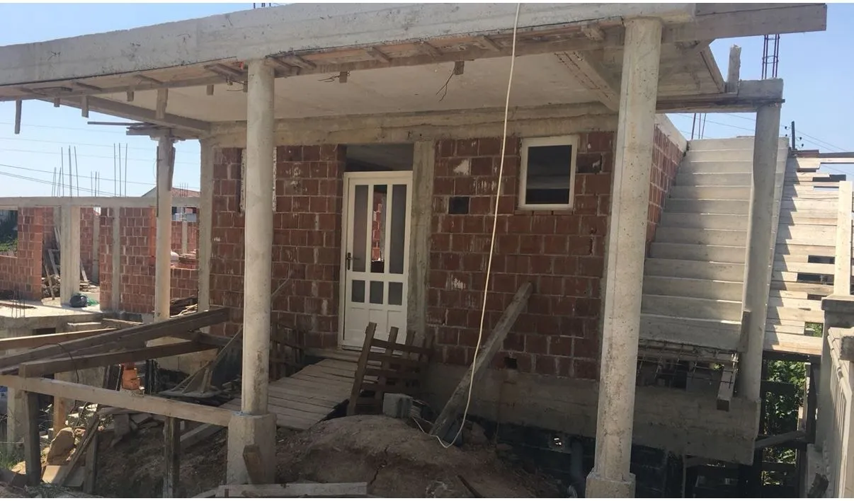A house under construction with concrete pillars and outdoor stairs.