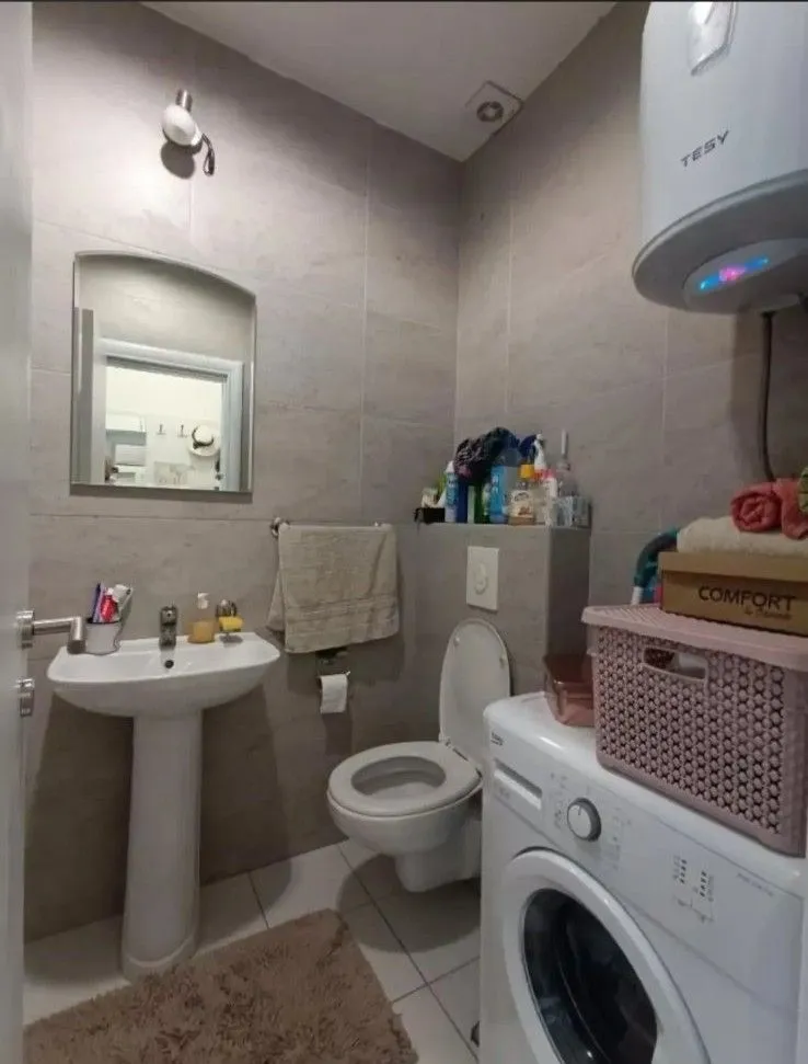 Smaller bathroom with a sink, toilet, washing machine, and water heater.