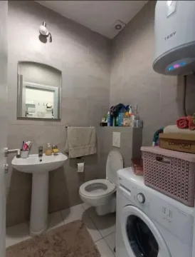 Smaller bathroom with a sink, toilet, washing machine, and water heater. - image 5