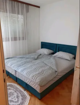 Pogled na urednu spavaću sobu sa bračnim krevetom i prozorom sa zavjesama. - image 6