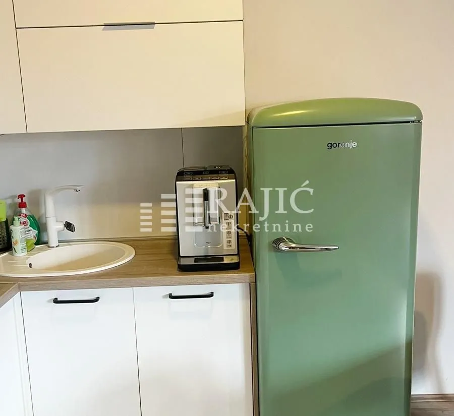 Part of the kitchen with a sink, coffee machine, and green refrigerator.