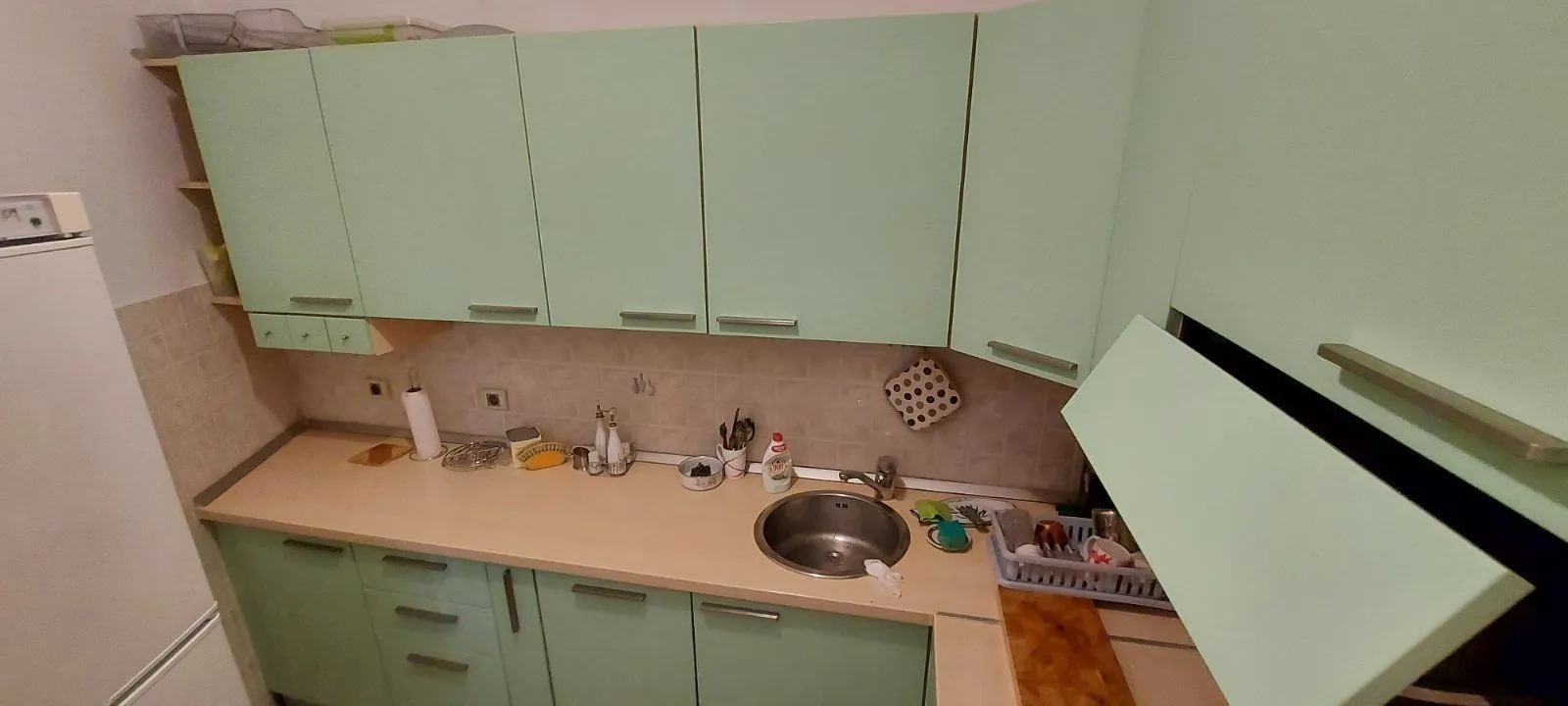Kuhinja sa svijetlozelenim elementima i radnom površinom.