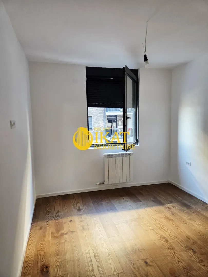 Empty room with wooden flooring, white walls, and a window.