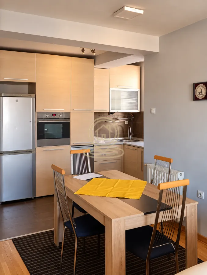 Kitchen with dining area equipped with wooden units and a table with chairs.