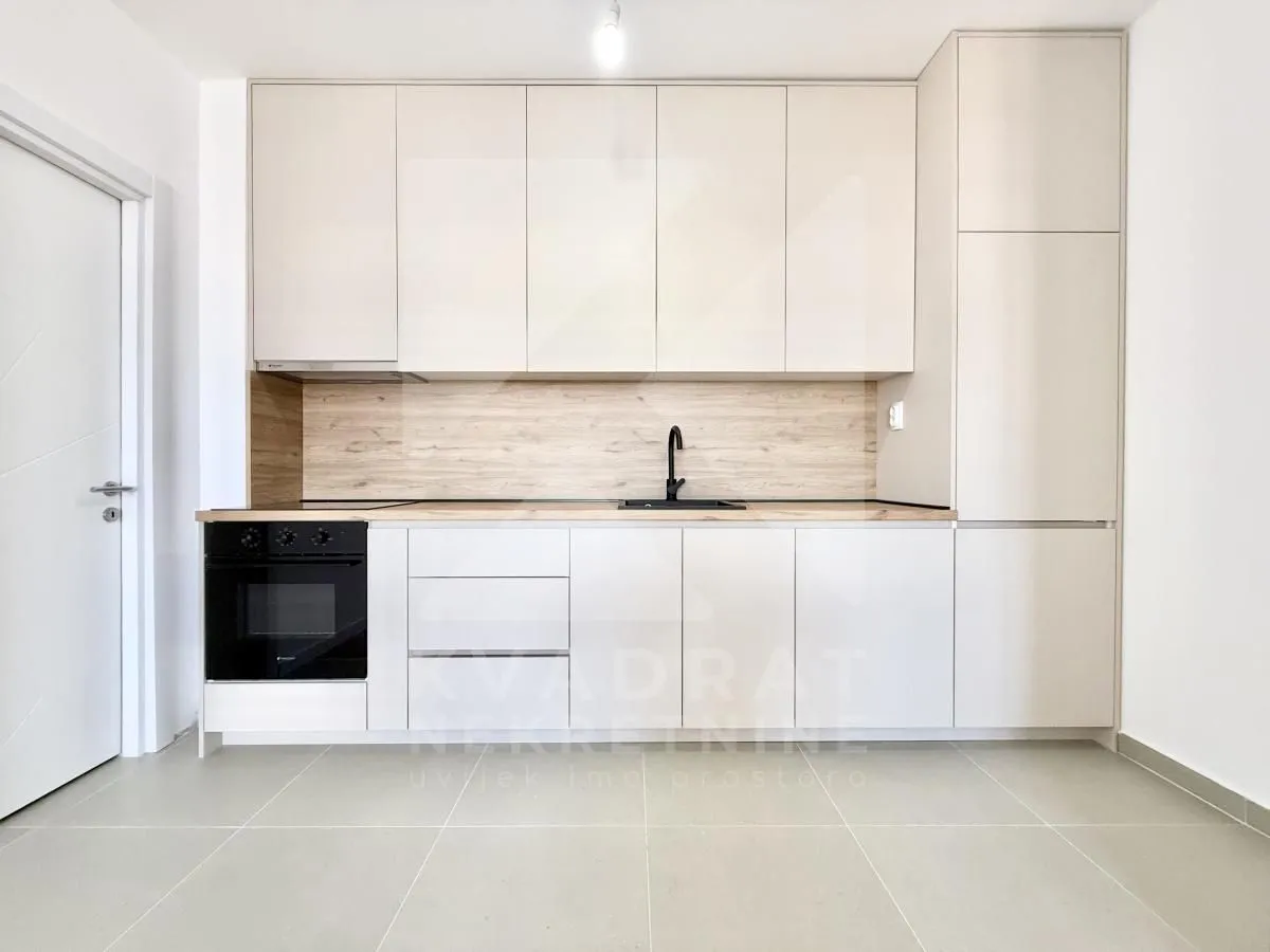Modern kitchen with light-colored cabinets and a built-in oven.