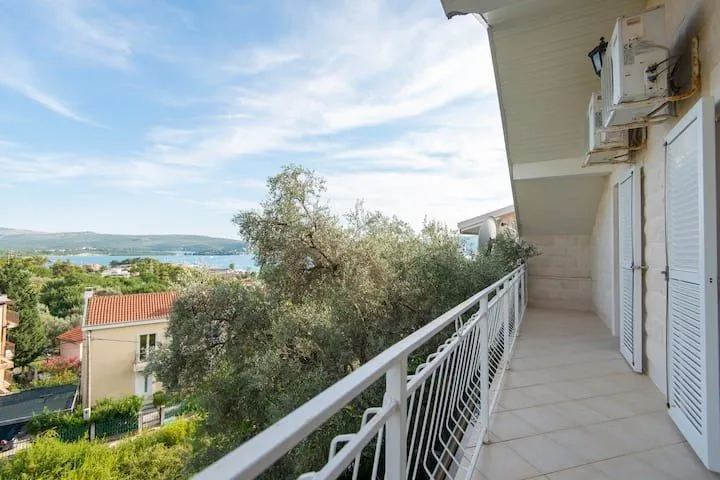 Prostrani popločani balkon sa ogradom i pogledom na more.