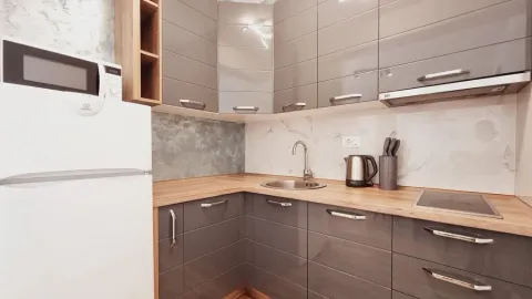 Modern kitchen with grey cabinets and a wooden countertop. - image 9
