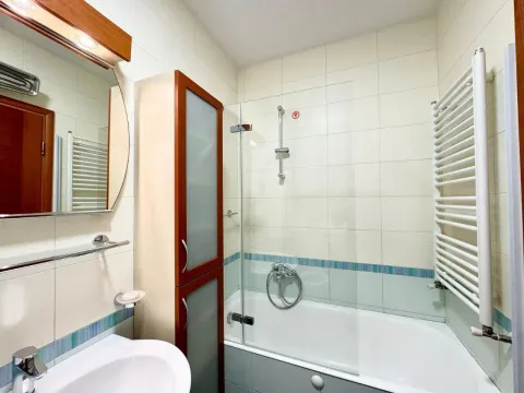 Compactly equipped bathroom with a bathtub, washbasin, and mirror. - image 15