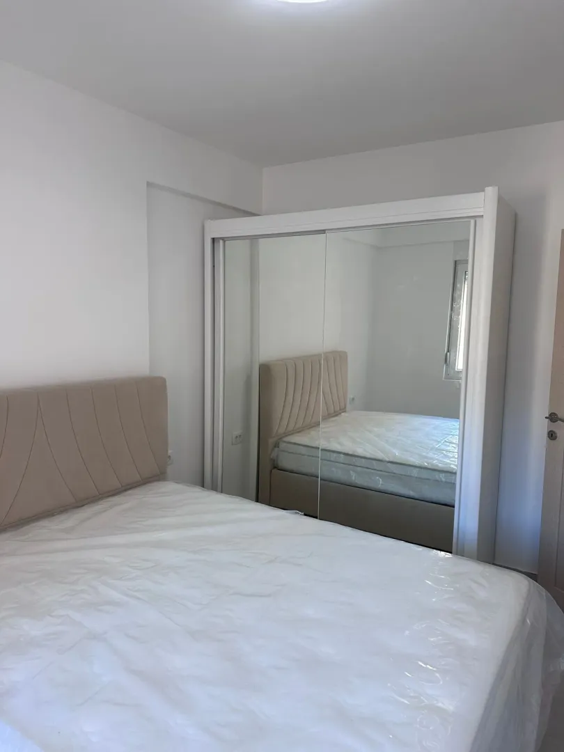 Furnished bedroom with a double bed and a large mirrored wardrobe.