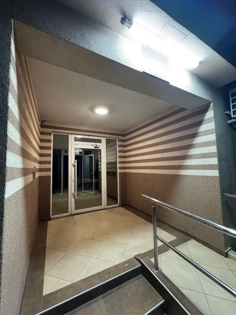 Entrance to a residential building with tiled stairs and glass doors.