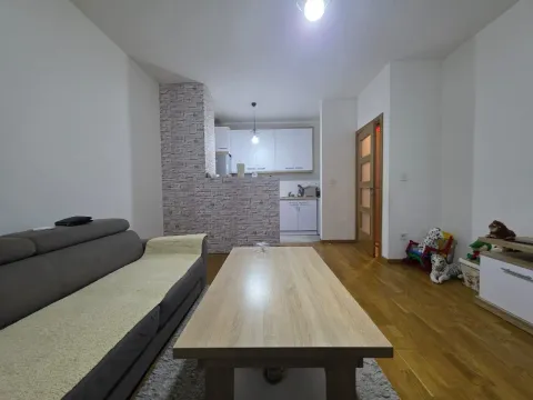 Pogled na dnevnu sobu sa garniturom i stolom, sa kuhinjom u pozadini. - image 7