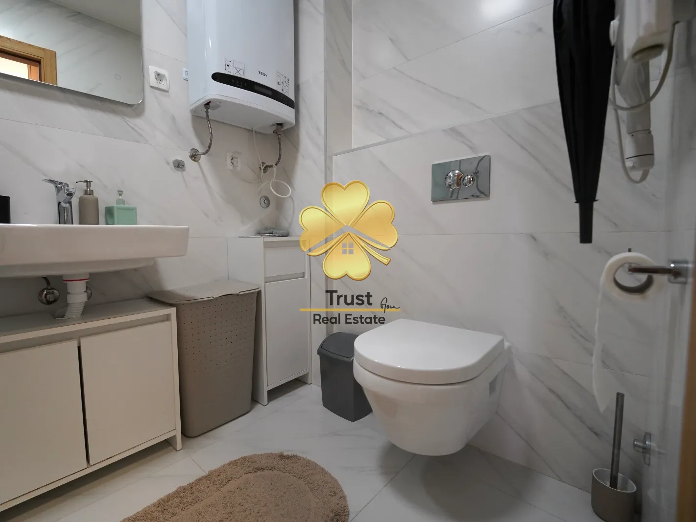 Modernly equipped bathroom with white tiles and toilet.
