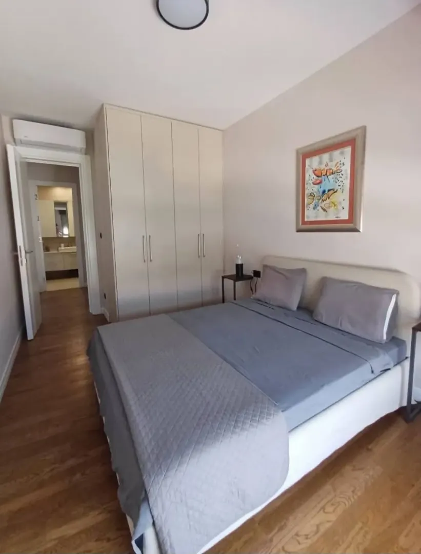 Furnished bedroom with a double bed, wardrobe, and a painting on the wall.