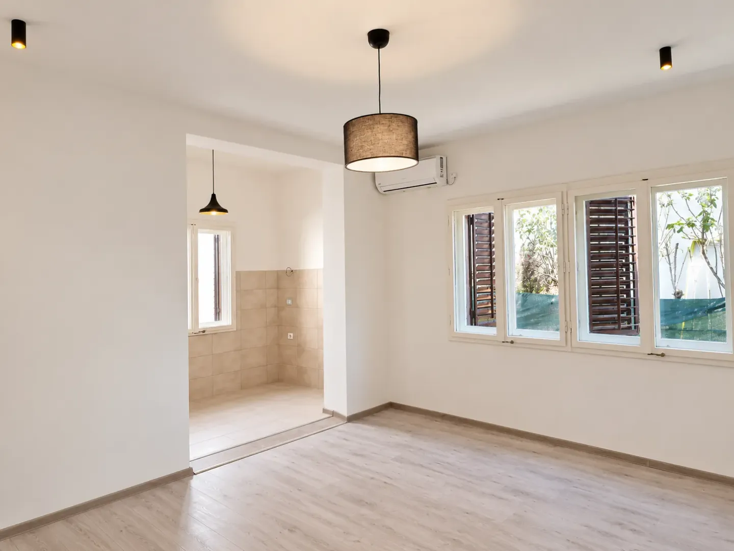 Empty living room with view of windows and passage to the kitchen.
