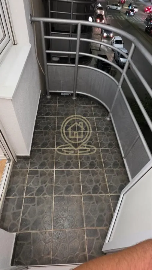 Manji popločani balkon sa metalnom ogradom i pogledom na ulicu.