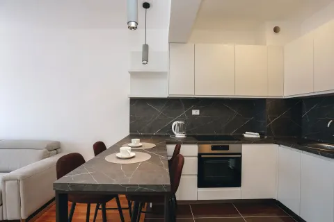 Modern kitchen with white cabinets and a dark countertop. - image 12