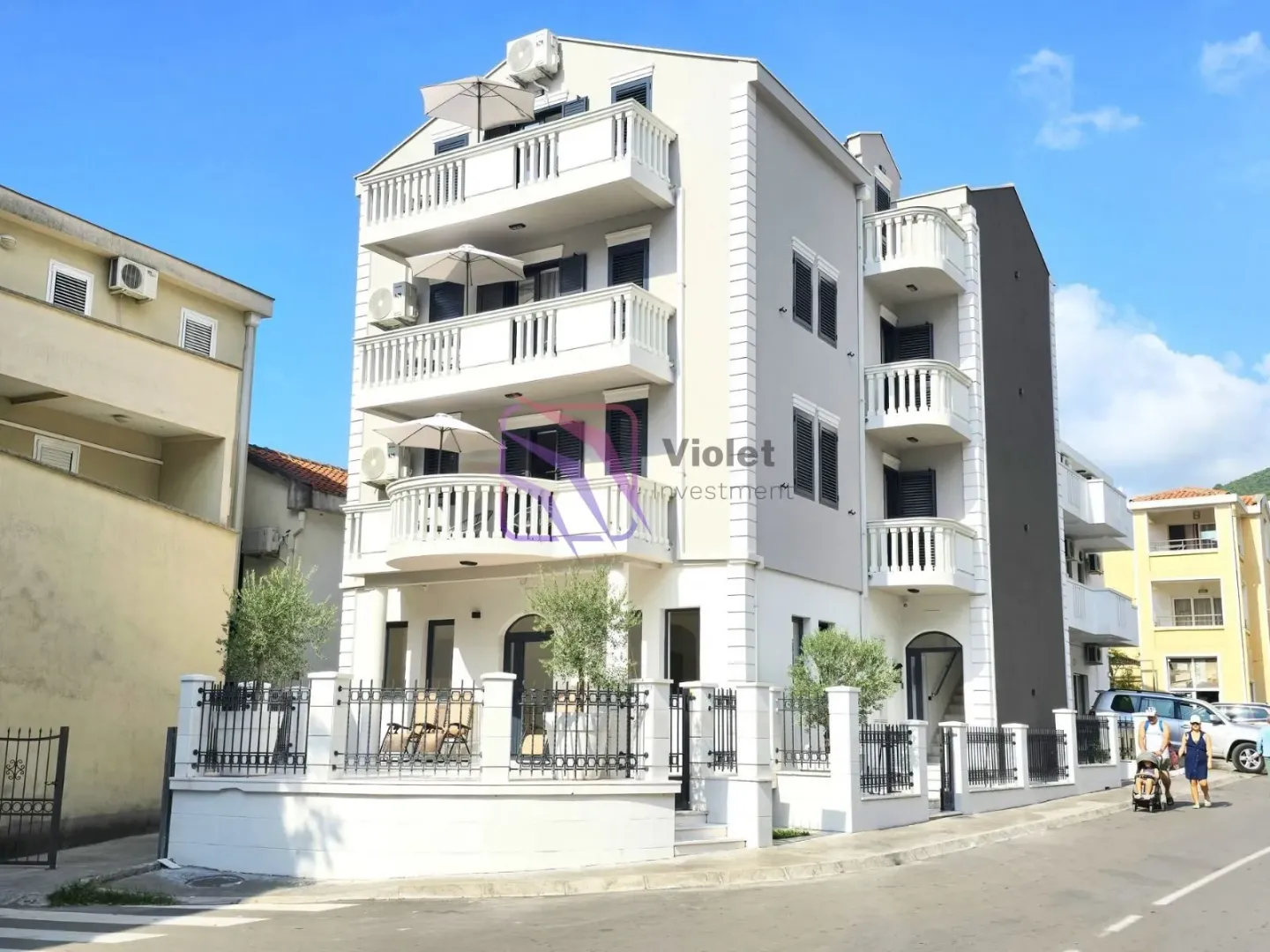 Exterior view of a multi-story residential building with balconies and a courtyard.