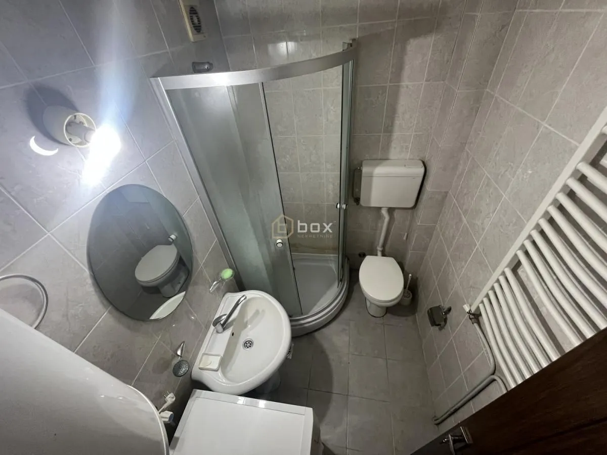 Small bathroom with a shower cabin, washbasin, toilet, and radiator.