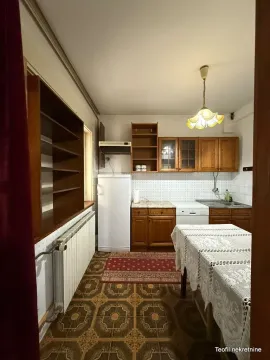 Starija kuhinja sa drvenim elementima, trpezarijskim stolom i frižiderom. - image 9