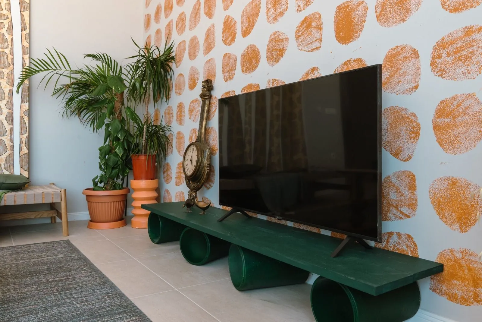 Dnevna soba sa televizorom na zelenoj polici i dekorativnim zidom.