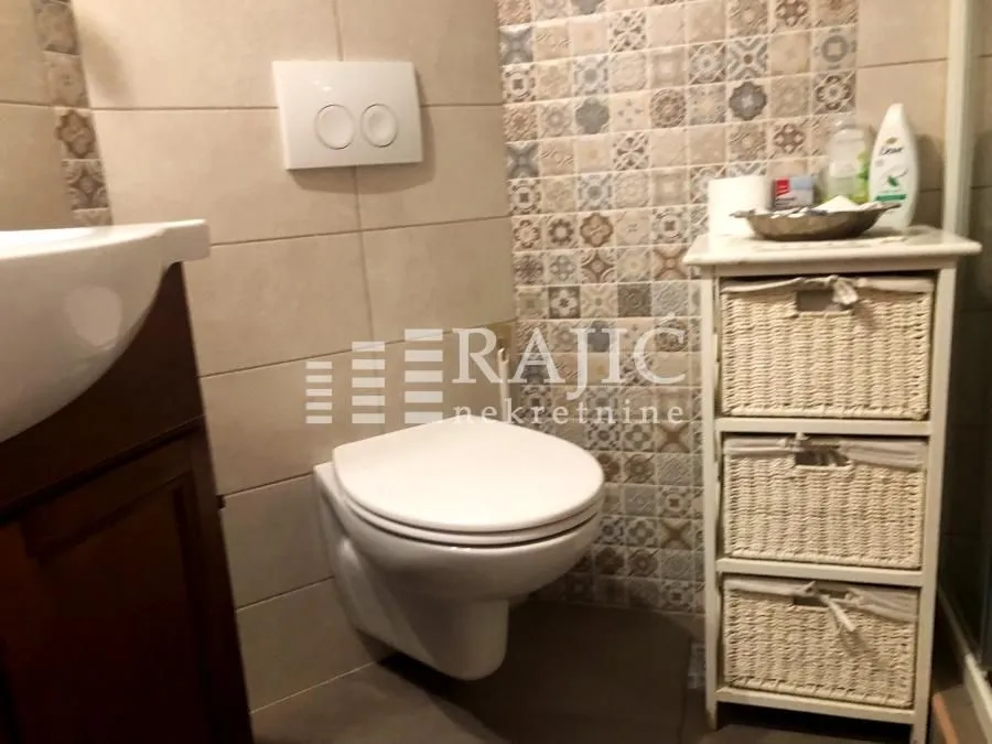 View of a part of the equipped bathroom with a toilet and tiles.