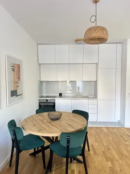 Moderna kuhinja sa bijelim elementima i trpezarijskim stolom sa zelenim stolicama. - image 3