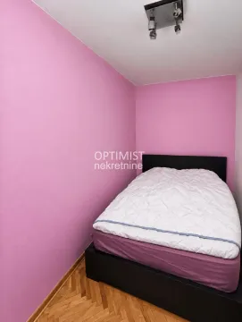 Manja spavaća soba sa krevetom i roze zidovima. - image 11