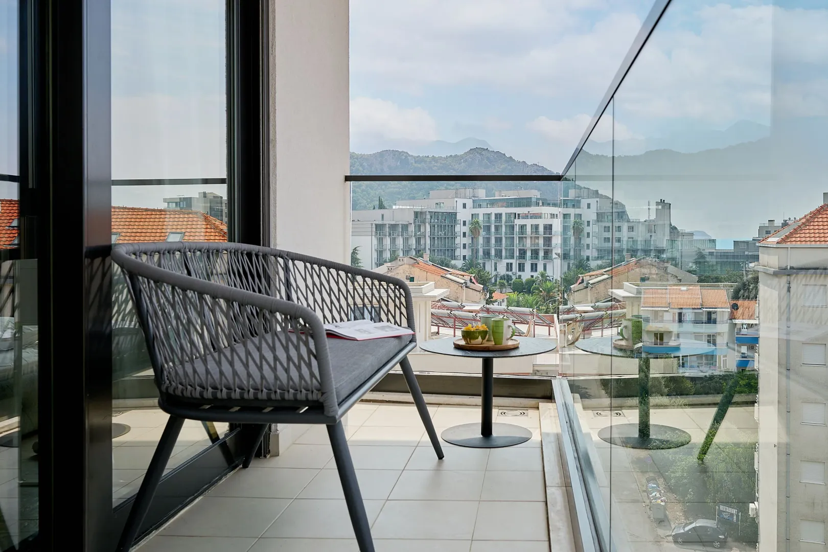 Namješten balkon sa staklenom ogradom i pogledom na grad.