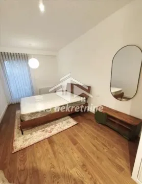 Spavaća soba sa bračnim krevetom, drvenim podom i ogledalom na zidu. - image 13