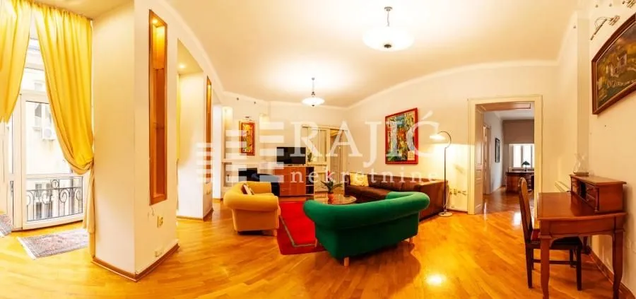 Spacious living room with seating furniture and parquet flooring.