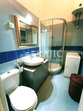 Smaller bathroom with a shower cabin, sink, and washing machine. - image 8