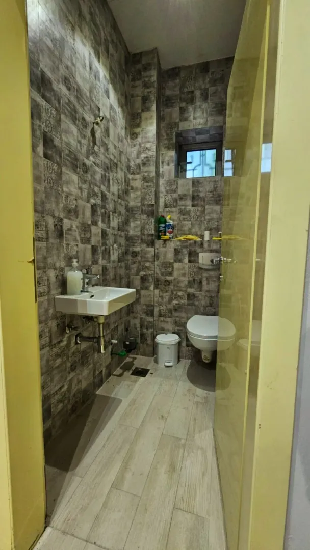 Bathroom with grey tiles, a sink, and a toilet.