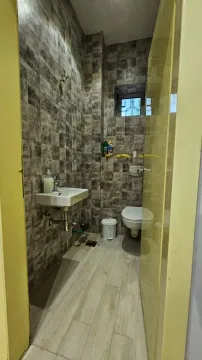 Bathroom with grey tiles, a sink, and a toilet. - image 7