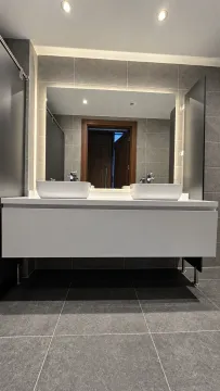 Modern bathroom with double sinks and a large mirror. - image 11