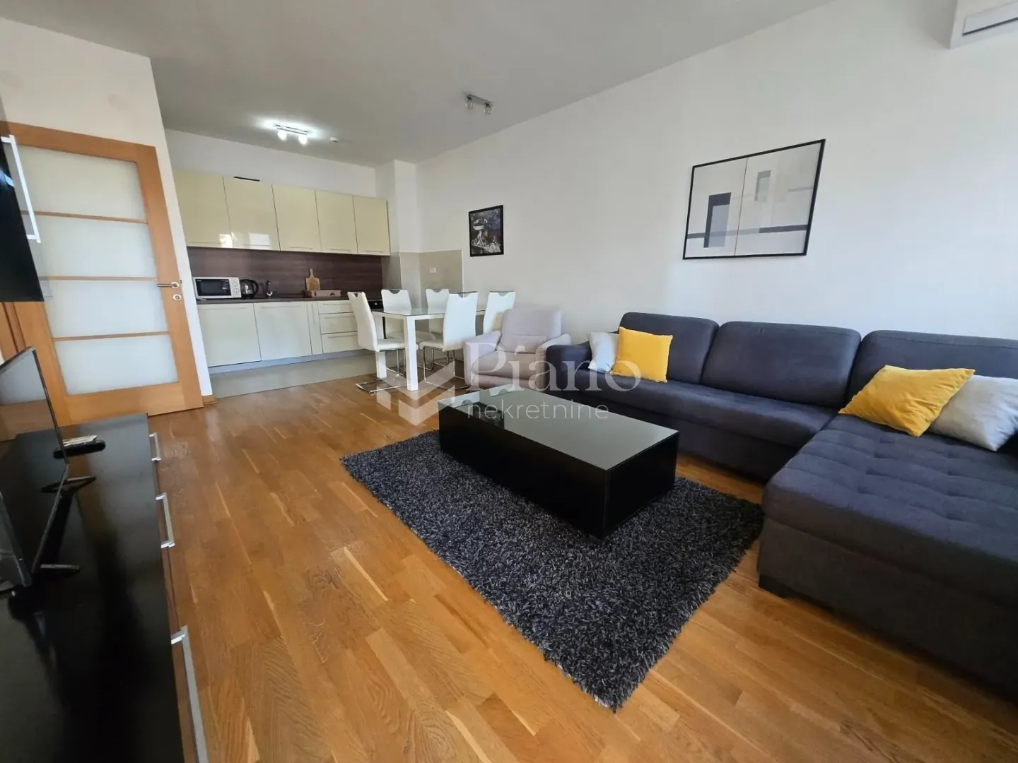 Dnevna soba sa garniturom i trpezarijom u sklopu kuhinje.