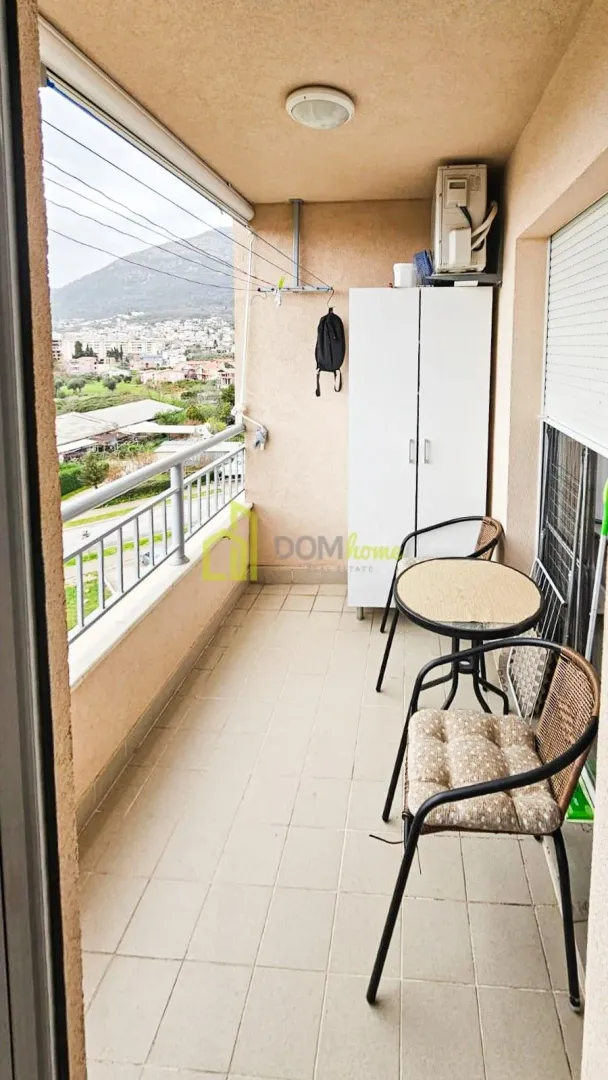 Covered balcony with seating furniture and city view.