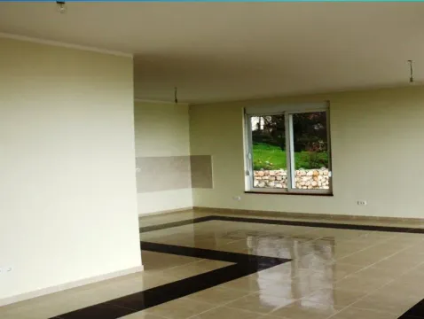 An empty, spacious room with tiled flooring and a view through the window. - image 3