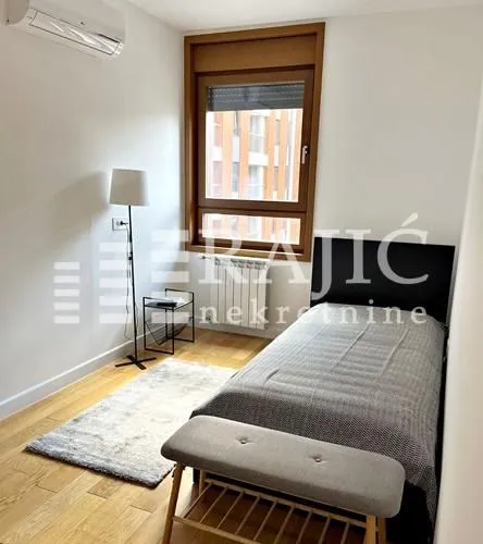 Small bedroom with a bed, lamp, and window.