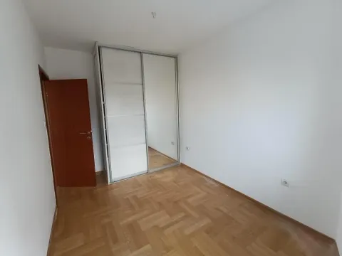 Prazna spavaća soba sa ugradnim ormarom i parketom na podu. - image 4