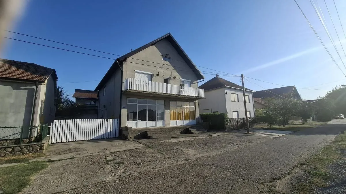 Pogled na prednju fasadu kuće sa dvorištem i ulicom u naselju.