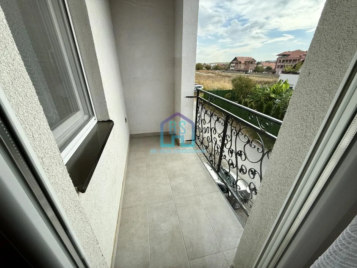 Nenamešten balkon sa metalnom ogradom i pogledom na okolinu.