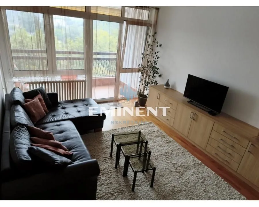 Living room with a sectional sofa, TV unit, and access to the terrace.