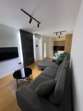 Modern living room with a sofa, coffee table, and TV, connected to the dining area and kitchen. - image 2