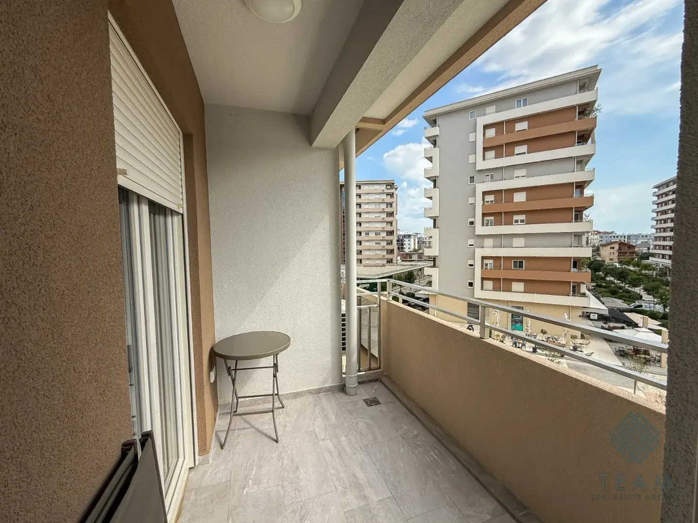 Covered balcony with a table and a view of surrounding buildings.