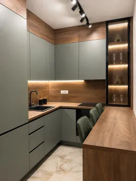 Modern kitchen with wooden elements, green cabinets, and a bar with chairs. - image 7