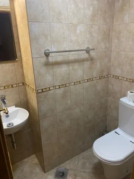 Jednostavno kupatilo sa toaletom, malim umivaonikom i zidnim pločicama bež boje. - image 16