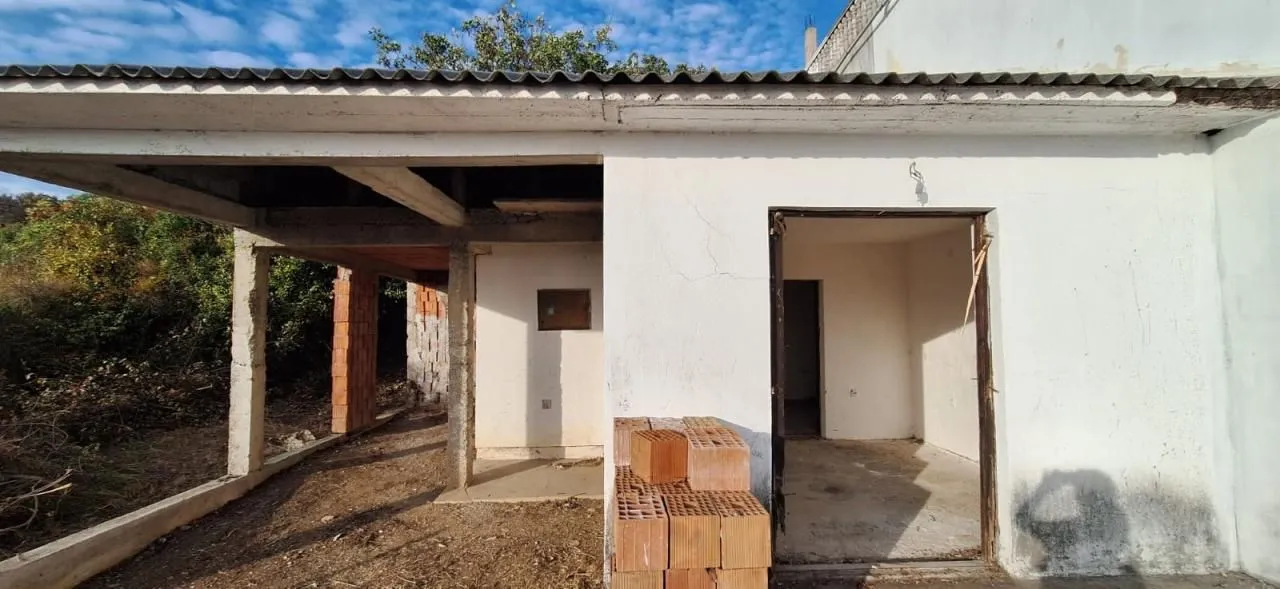 Pogled na spoljašnjost kuće u izgradnji sa otvorenim ulazom i građevinskim materijalom.