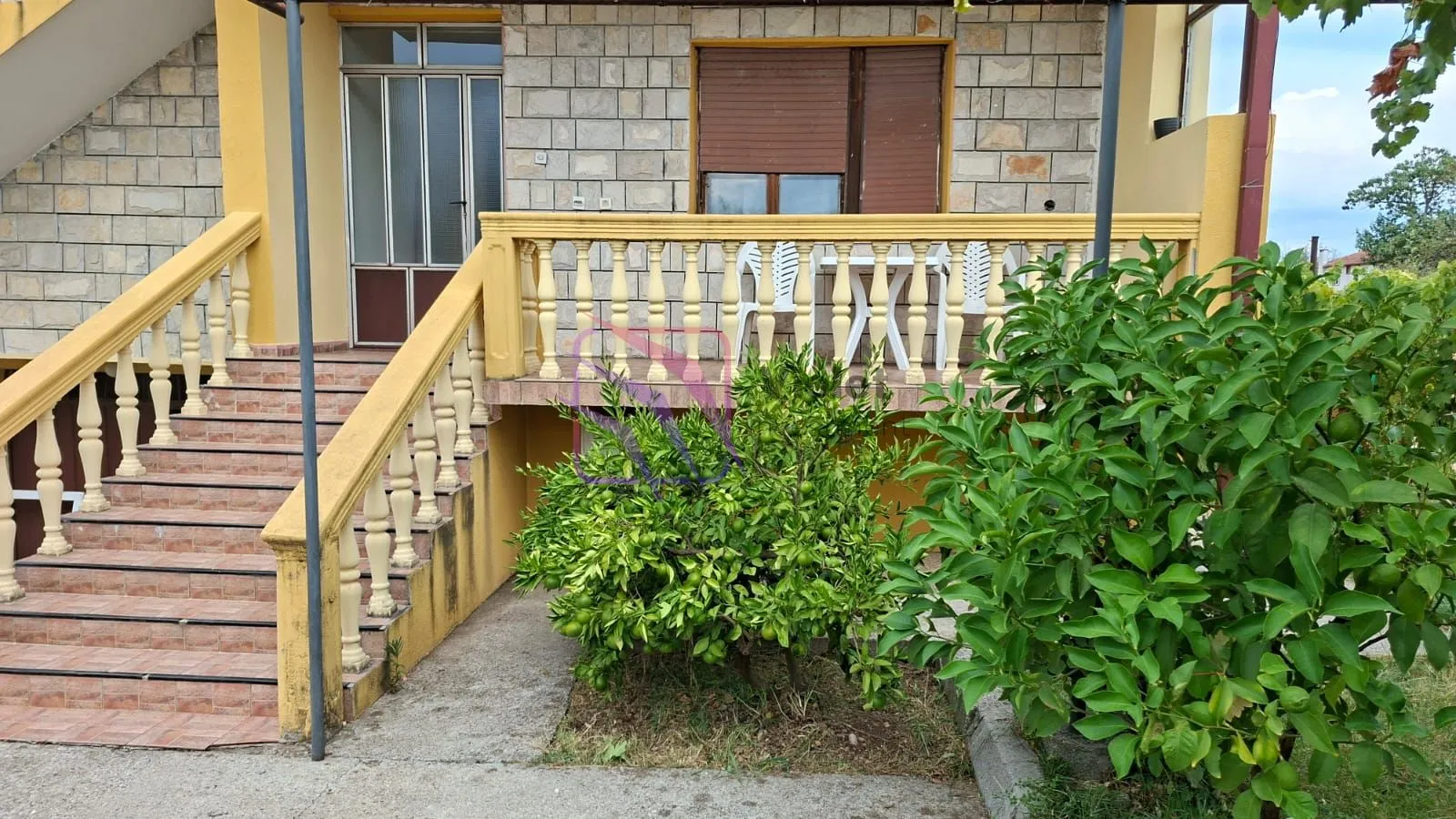 Entrance to the house with stairs, terrace and landscaped yard.