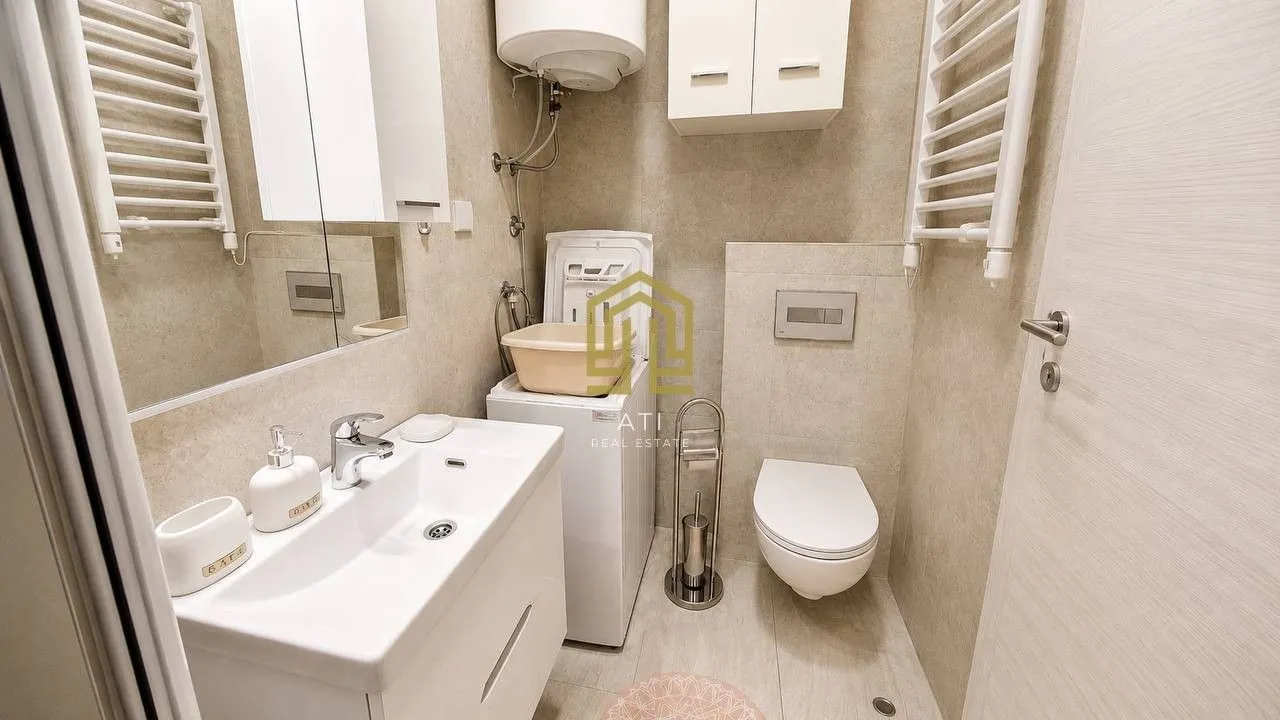 Modern bathroom with a sink, toilet, and washing machine.